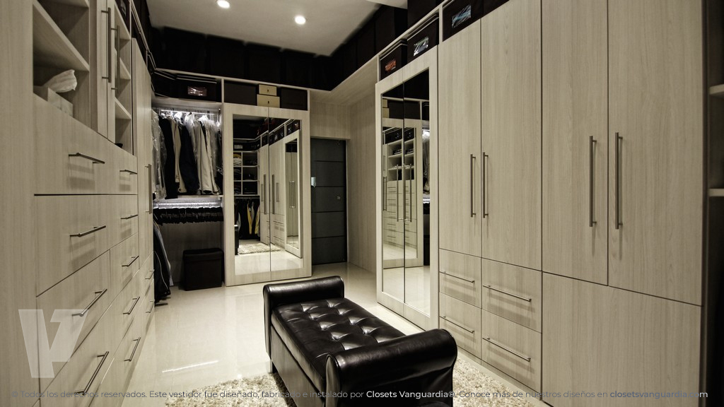 02-vestidor-walkin-closet-con-puertas-de-espejo-y-luz-en-esquina-color-claro-blanco-teka-artico-y-taburete-en-el-centro-closets-vanguardia.jpg